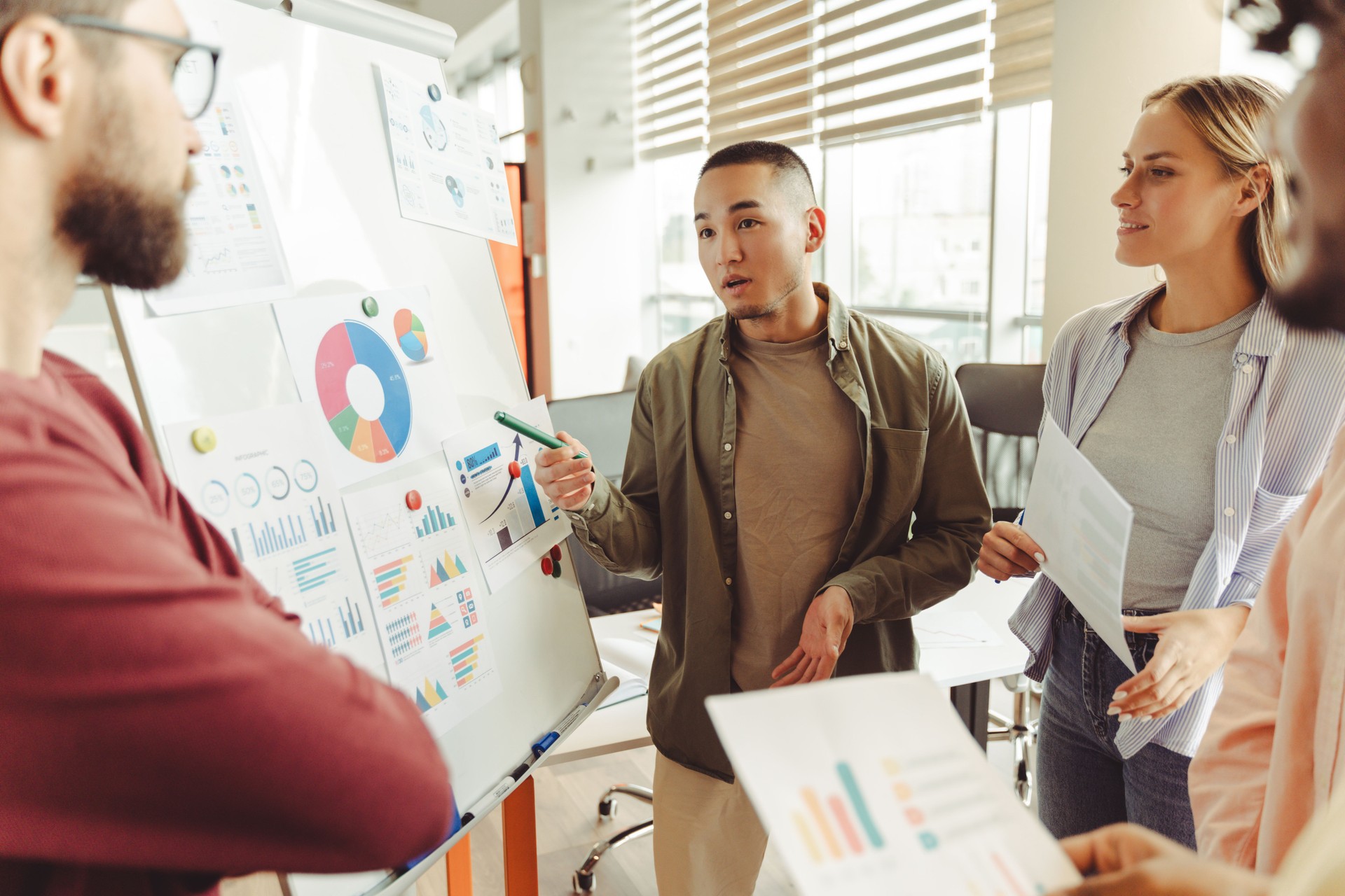 Diverse team analyzing charts on whiteboard during brainstorming session